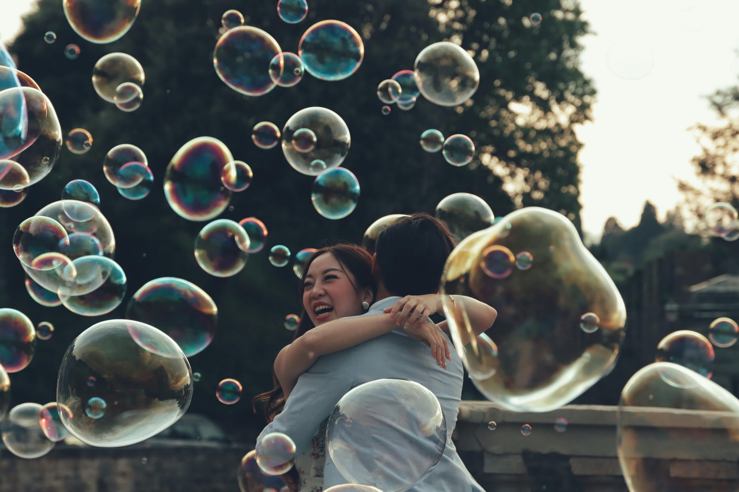 The Hidden Trap of Idealizing Love A joyful couple hugging surrounded by bubbles, set outdoors in Florence, Italy.